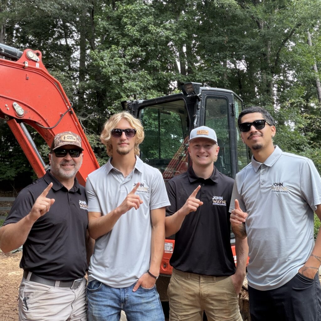 The John Wayne Clearing & Grading team standing in front of excavator equipment ready for land clearing and excavation projects.