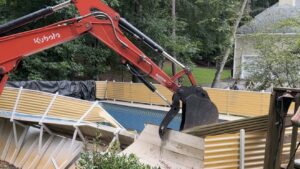 Excavator demolishing an inground swimming pool during a residential pool removal project in Metro Atlanta, Georgia.